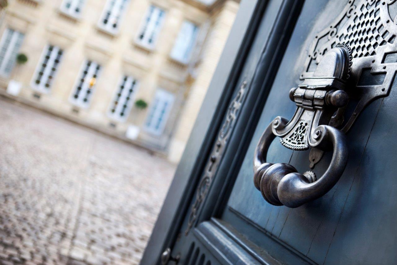 Ornate door with knocker, opening into a grand courtyard